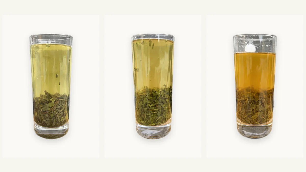 A glass cup of pale green tea on a wooden tray during tea tasting in Shanghai, China